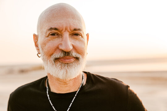 Bold senior man with beard looking at camera outdoors