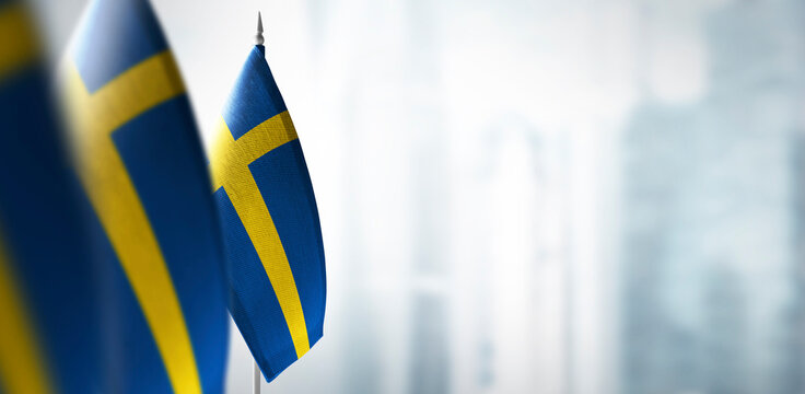 Small flags of Sweden on a blurry background of the city