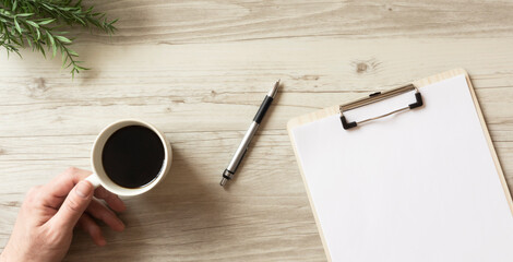 The man who is writing notes on the documents on a table. テーブルの上の資料にメモを書いている人