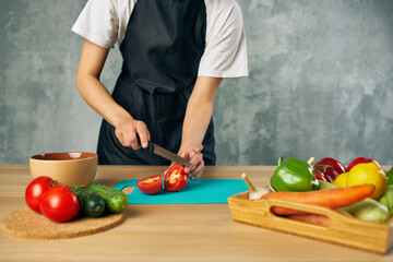 Cook in black apron on the kitchen cutting vegetables salad diet