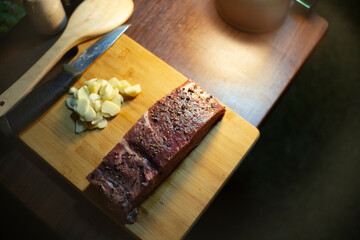High-quality beef served on a wooden chopping board and seasoned with spices for a late-night party.