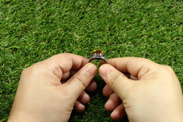 Hand holding classic silver ring with natural yellow sapphire. Abstract meaning of proposal...