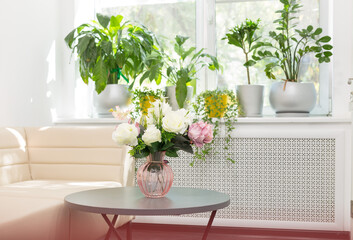 artificial flowers on a glass bottle, a bouquet of silk flowers on a black table next to a leather sofa