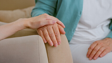 Caregiver cheers up senior lady patient touching hand while sits in armchairs in light room - 459843484