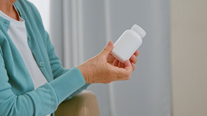 Mature woman patient takes blank white bottle of medicine from doctor sitting in comfortable armchair
