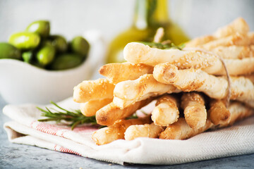 Italian grissini breadsticks with sesame and rosemary on a light background, selective focus, close-up, horizontal orientation
