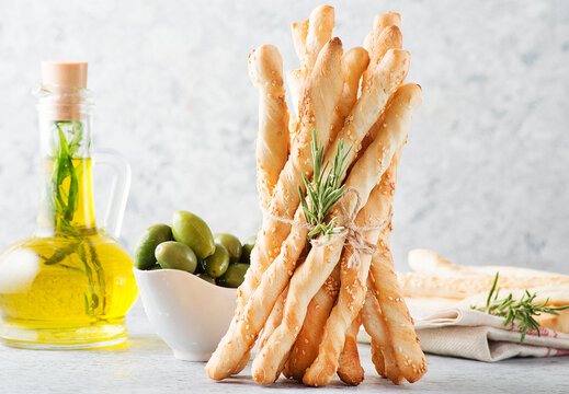 Italian bread sticks with sesame seeds and herbs on a light background, selective focus