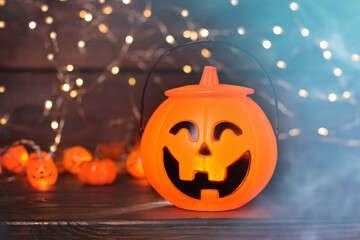Glowing Halloween handbag in the form of a pumpkin, glowing garland in the form of a pumpkin on wooden background with bokeh lights.Halloween trick or treat!Сopy space for text.Halloween background