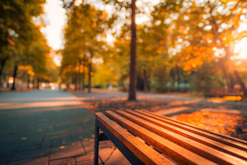 Naklejka na ściany i meble Fall park bench autumn urban landscape recreation. Peaceful relaxing sunset closeup of wooden bench with blurred bokeh forest tress, sun rays. Idyllic seasonal nature concept, dreamy October landscape