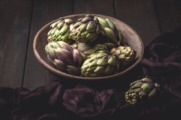 Obraz premium Fresh artichoke on the dark,wooden background. Ingredients of Mediterranean cuisine, rustic style 