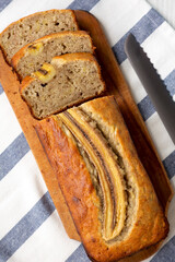 Homemade Banana Bread on a rustic wooden board on a white wooden background, top view. Flat lay, overhead, from above.