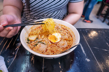 women eating pork noodle tom yum with egg on blurred wooden