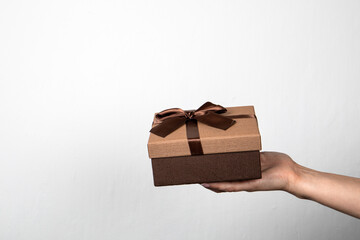 Brown gift box with a ribbon in a woman's hand. Free space for advertising and text