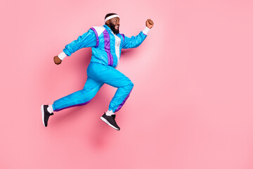 Fototapeta na wymiar Photo of impressed cute dark skin man wear blue suit headband jumping high running looking empty space smiling isolated pink color background