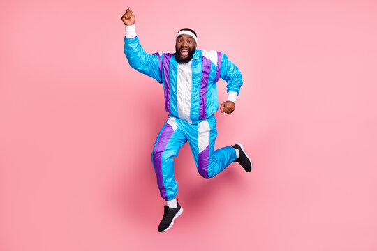 Photo Of Pretty Sweet Dark Skin Guy Dressed Sport Suit Headband Smiling Jumping High Running Fast Isolated Pink Color Background