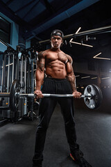 Fototapeta na wymiar Strong and muscular afro-american man trains on modern equipment in gym. Portrait of muscular pumped up fitness trainer