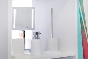 Assortment of white bathroom household goods, liquid soap dispenser on the shelf, toothbrush glass,...
