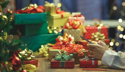 Woman on sweater typing on mobile phone for online messaging and social communication under vivid night lights of gorgeous festival party in winter season