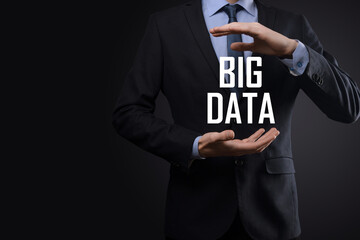 Businessman in a suit on a dark background holds the inscription BIG DATA. Storage Network Online Server Concept.Social network or business analytics representation