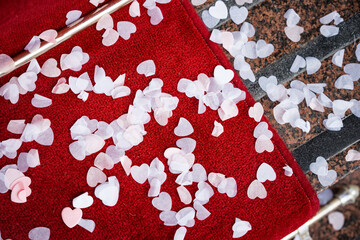 Beautiful wedding confetti love heart shape scatter on red carpet after being thrown over bride and groom to celebrate marriage ceremony. Romantic love hearts on the ground.