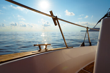 Deck of white yacht sailing in open sea at sunset