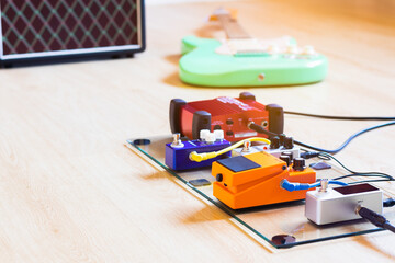 colourful pedal effect board, electric guitar and amplifier on floor. music background