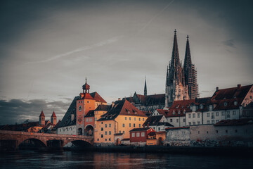 View from the Danube on the Regensburg Cathedral and Stone Bridge with lights in Regensburg in the evening, Germany