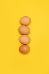 Tasty brown chicken eggs and one broken egg with yolk on yellow background