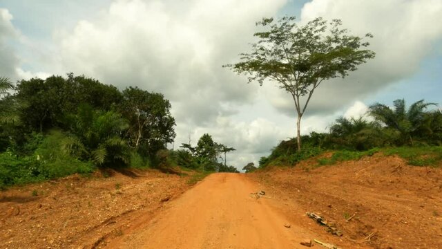 Tropical forest jungle trail rural Ghana Africa drive POV. Rural forest and mountain valley tropical jungle environment. Dirt roads and trails used for transportation. Landscape green trees tropical/