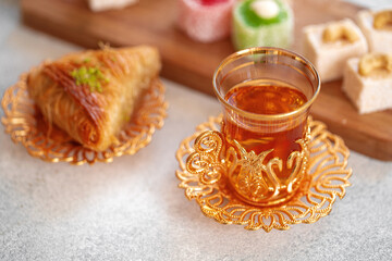 Various Turkish sweets and cup of tea on white textured background