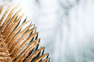Gold palm leaves and shadows on a blue wall background.