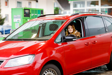 Young attractive woman with happy positive expression, being satisfied with unforgettable journey by car, sits on driver seat. People, driving, transport concept. Winter ski holiday by car