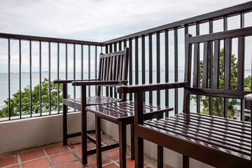 Empty brown wood chair and table set on balcony on high rise building with sea view