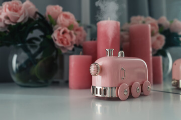 Stylish smoking aroma diffuser in the form of a steam locomotive on the table. Women's space, a cozy workplace.