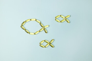 Fish oil omega 3 capsules are arranged in the shape of a fish on a blue background