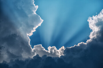 The sun beams break through the dark cumulus clouds.