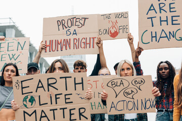 young students protest on the street with boards against climate change - Youth activists...