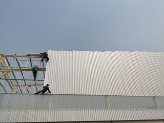 three workman is installation metal sheet siding of factory roof, Working at height, worker is adjustable roof for warehouse,