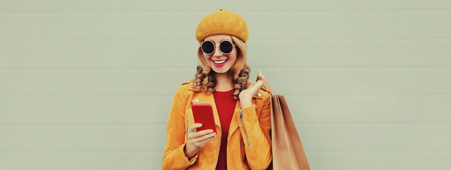 Autumn portrait of happy smiling young woman taking a selfie by smartphone with shopping bags...