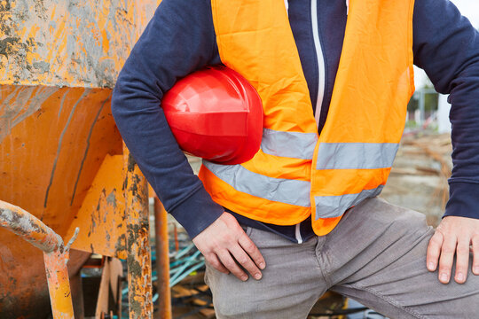 Worker wears red hard hat under his arm on construction site
