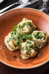 Manti dumplings with minced lamb meat on orange plate on the table