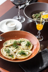 Polish Pierogi or Vareniki dumplings stuffed with potato served with dill on orange plate