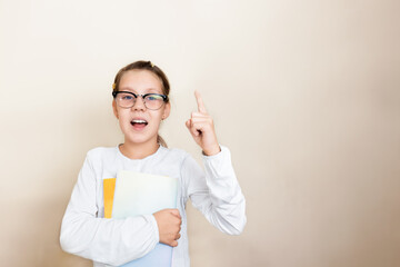 child girl with glasses raised her index finger up and the second hand holds books. concept....