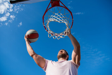 muscular man player throw basketball ball through basket, male basketball © Olena