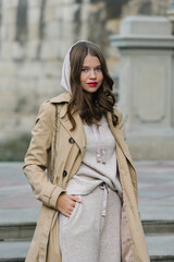 Portrait of fashionable women in beige sports suit and trench coat posing on the street