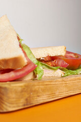 Sandwich with tomato an lettuce, wood board table