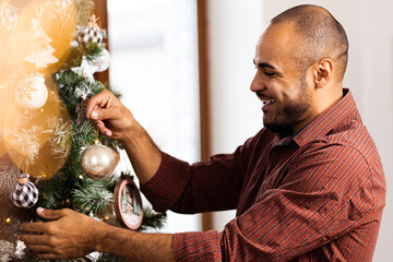 African American man decorating Christmas tree at home