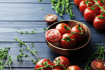Composition of fresh ripe cherry tomatoes, thyme and spices on blue wooden background