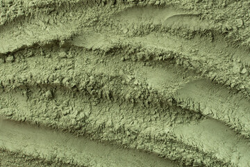 Texture of dry green cosmetic clay with brushstroke top view. Abstract background of seaweed green...