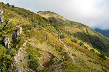 rear view of young woman in yellow hoodie in hood with backpack hiking in picturesque mountain valley healthy active lifestyle digital detox, weekend activities